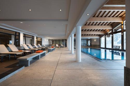 拉赫兹耶尔Hôtel Alpen Lodge的一座带桌椅的游泳池