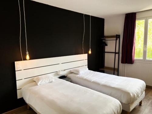 日安Brit Hotel Confort Gien的一张黑墙客房内的两张床