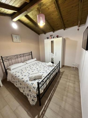 卡塔尼亚Mimì e Cocò shabby house的一间带一张大床的卧室,位于一个拥有木制天花板的房间