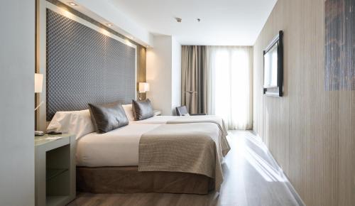 巴塞罗那加泰罗尼广场酒店的一间设有大床和窗户的酒店客房