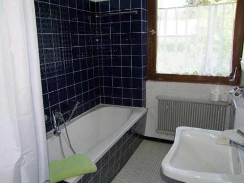 NeuglashüttenHaus Elisabeth - Ferienwohnung Hirschsprung, 2 Schlafzimmer, Feldberg的蓝色瓷砖浴室设有浴缸和水槽