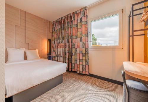 索西姆B&B HOTEL Mulhouse Sausheim的酒店客房设有床和窗户。