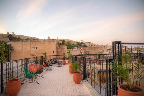 非斯Riad Sekaya Fez的大楼内的阳台配有椅子和盆栽植物