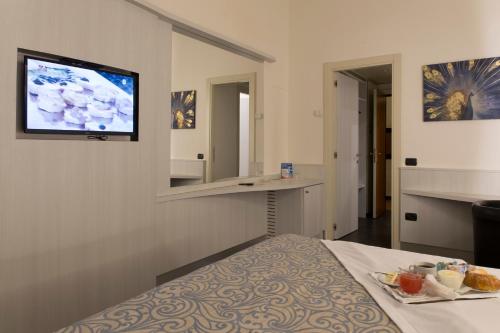 莱尼亚诺Hotel City Legnano的酒店客房设有一张床和墙上的电视