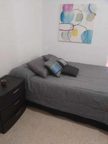 圣胡安Hermoso Apartamento frente Aeropuerto de Isla Verde的卧室内的一张带两个枕头的床和梳妆台