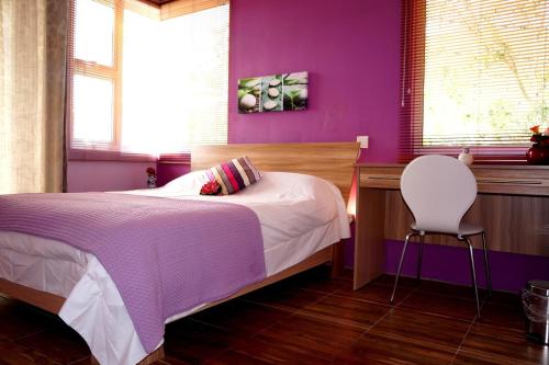 拉戈莱特勒莫纳齐特别墅的紫色卧室配有一张床和一把椅子