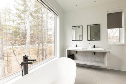 La ConceptionChalet Vintersaga Mont Tremblant的白色浴室设有两个盥洗盆和大窗户。
