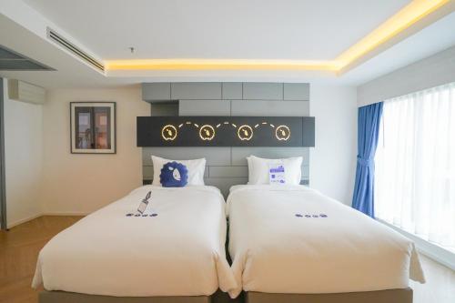 Ban Prong Phra Bat Nok (1)Kokotel Chiang Rai Airport Suites的一间卧室配有两张带白色床单的床