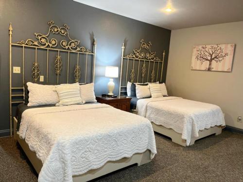 Lake ArthurThe Bank Hotel的一间卧室配有两张带白色床单和金色装饰的床。