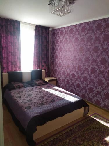 博斯特里Нур пансионат的一间卧室配有一张带紫色壁纸的大床
