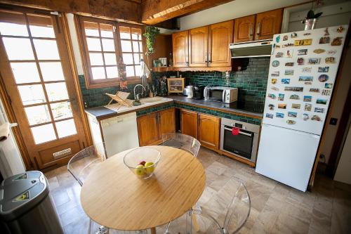 弗农Chambres d Hôte Bords de Seine Vernon-Giverny的厨房配有木桌和白色冰箱。