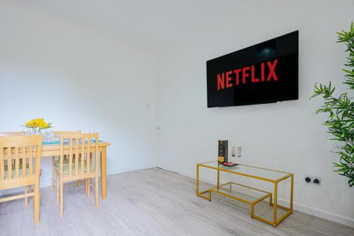 卢顿Modern Freshly Refurbed Home Luton的一间设有桌子的用餐室和墙上的电视