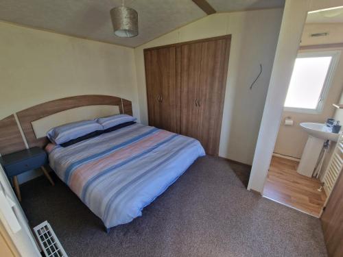 英戈尔德梅尔斯B17 Sunnymede Caravan Park, Fantasy Island, Ingoldmells的一间卧室设有一张大床和一个水槽