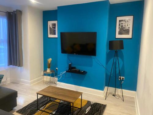 滨海绍森德The Sailsbury Snug的客厅设有蓝色墙壁和平面电视。