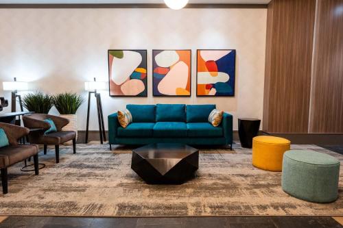 温哥华戴维桑德曼套房酒店的客厅配有蓝色的沙发和一些椅子