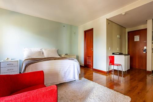 巴西利亚Flat - Comfort Suítes - Localização e Conforto的一间卧室配有一张床和一张红色椅子