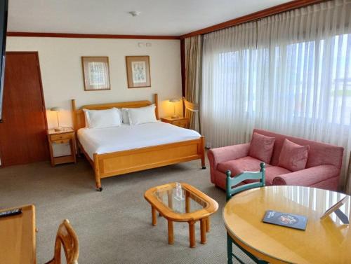 蒙特港abba Presidente Suites Puerto Montt的酒店客房配有床、沙发和桌子。