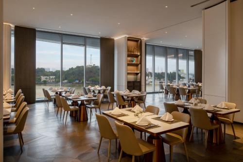 广州洲至奢选广州香岚官洲酒店的餐厅设有桌椅和大窗户。
