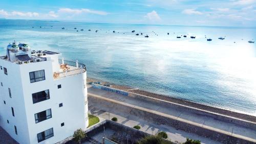 Cu Lao ThuIsland Sunset Hotel - Đảo Phú Quý的一座白色的建筑,在海洋里鸟儿们