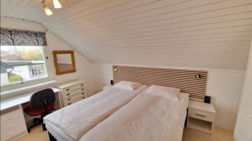 锡姆里斯港Vindsvåning i Simrishamn的一间卧室配有一张床、一张书桌和一个窗户。