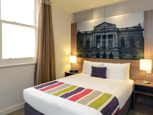 阿德莱德Grosvenor Hotel Adelaide的酒店客房的墙上设有一张带绘画的床铺。