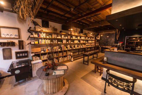 丰冈市Book & Guesthouse Hitotomaru的一间房间,有很多书架和一张桌子
