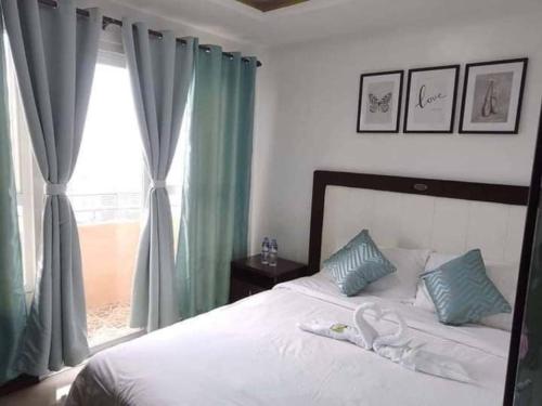 马尼拉Robinson manila birchtower的一间卧室配有一张带绿色窗帘的床和窗户。