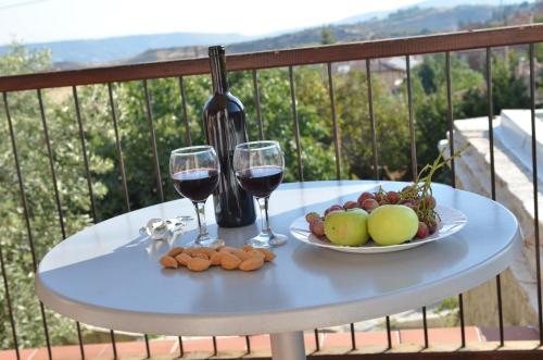Vouni沃尤尼旅舍的一张桌子,上面放着两杯葡萄酒和一盘水果