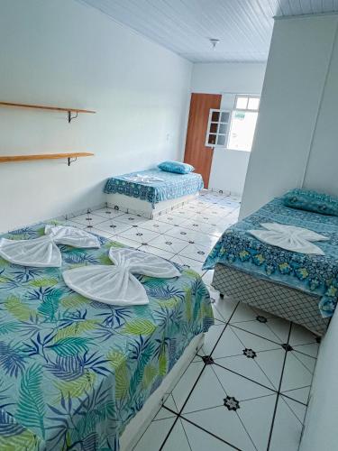 伦索伊斯Pousada Sempre Viva Lençóis的客房设有两张床,铺有瓷砖地板。