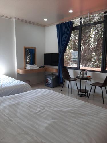 三岛县Galaxy Hotel的一间卧室配有一张床、一张书桌和一个窗户。