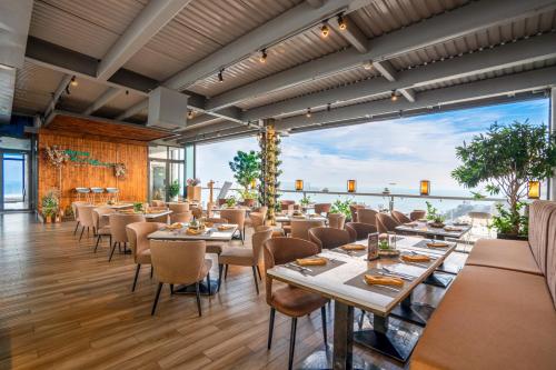 头顿Premier Pearl Hotel Vung Tau的餐厅设有桌椅和大窗户。