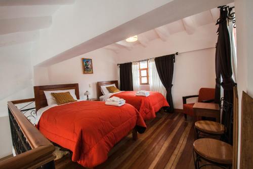 SicuaniWilkamayu Hotel的一间卧室配有两张带红色床单和椅子的床