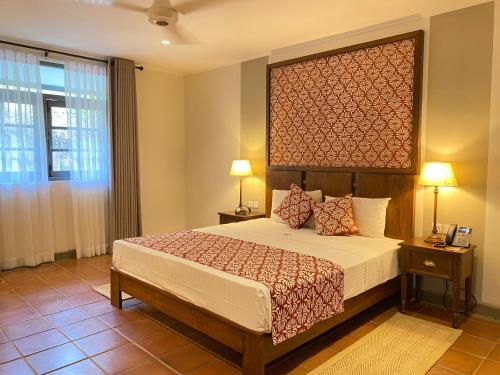 尼甘布Tamarind Tree Garden Resort - Katunayake的一间卧室配有一张带大床头板的床