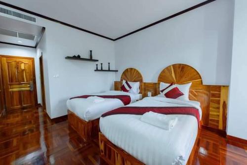 武里南Sky View Hotel Buriram的配有白色墙壁和木地板的客房内的两张床