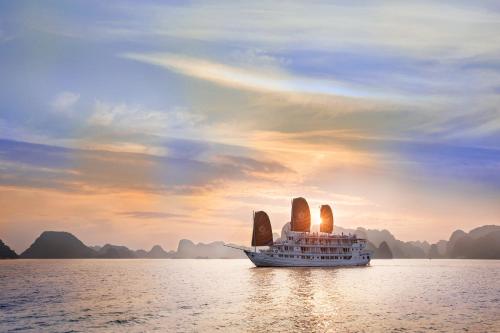 下龙湾Hera Cruises Group on Ha Long Bay的日落时分在水面上航行的两艘船