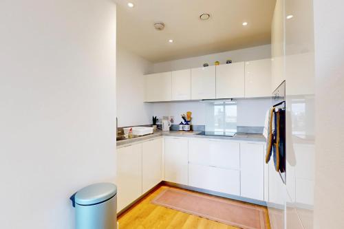 伦敦2 Bed Apartment with Balcony - 2 min to Station的厨房铺有木地板,配有白色橱柜。