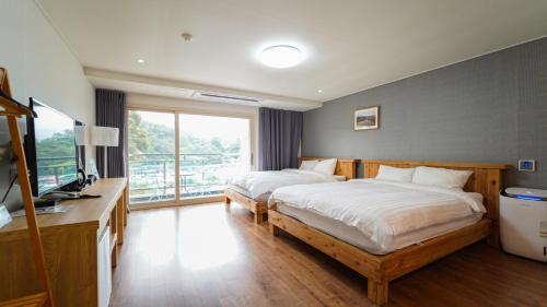 西归浦市천지연크리스탈 하버39호텔的一间卧室配有两张床、一张桌子和一台电视。