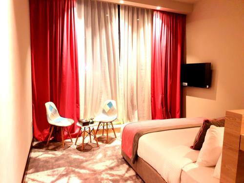 迪拜FORTUNE ATRIUM HOTEL的一间卧室配有红色窗帘、一张床和两把椅子