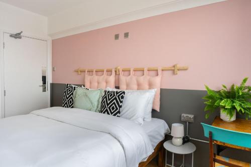 利物浦PH Hostel Liverpool的一间卧室设有两张床和粉红色的墙壁