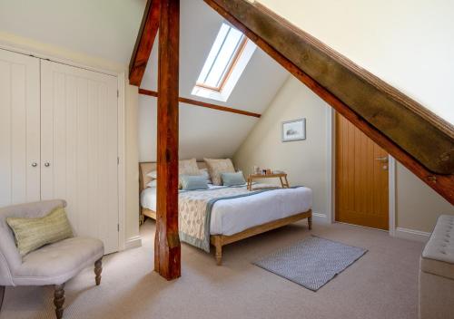 布莱克尼Boat Barn Cottage的阁楼卧室配有床和椅子