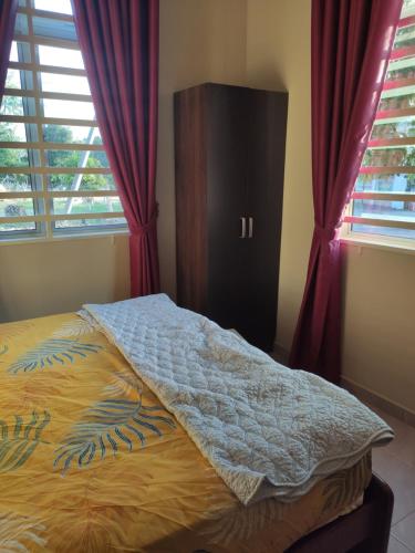 阿罗士打ABHAR Inap Desa的卧室内的一张床位,卧室内有红色窗帘和窗户