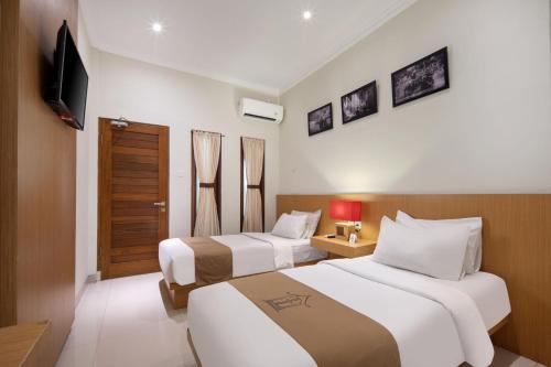 库塔Angkul Angkul Segara Beach Kuta by Kamara的酒店客房设有两张床和电视。