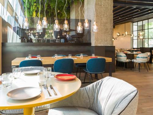 塞维利亚Novotel Sevilla的用餐室配有桌椅和灯光