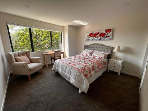 奥克兰Brand New & Central - 3 Bedrooms with 3 En suites的卧室配有床、椅子和窗户。