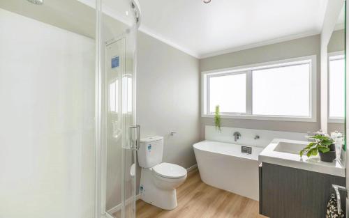 帕拉帕拉乌穆Sunshine Haven - New 3-Bedroom 4-Beds in Paraparaumu的浴室配有卫生间、浴缸和水槽。