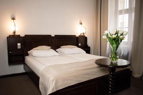 弗罗茨瓦夫杜沃尔波兰语酒店的一间卧室,配有一张带花瓶的桌子