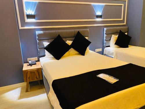 ArnavutköyiNALENS AİRPORT HOTEL的一间卧室配有两张带黑色和黄色枕头的床