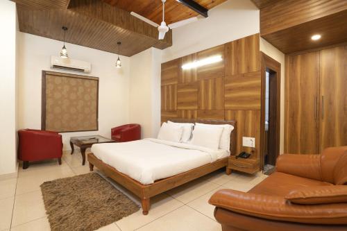 希萨尔Hotel Razia inn " A Unit of Sihag Construction & Real Estate Pvt Limited "的一间卧室配有一张床、一把椅子和一张沙发