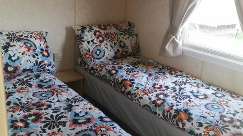斯凯格内斯3-Bed 8 berth static caravan in ingoldmells的一张小房间的床,配有花卉床罩