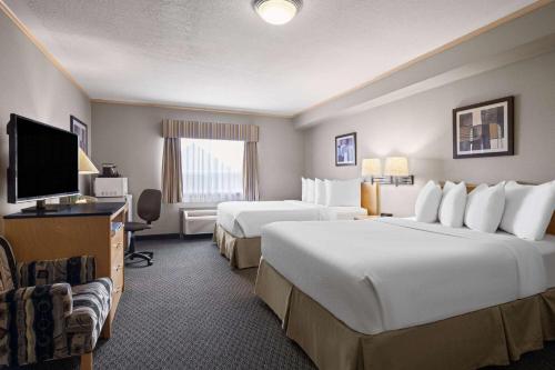 麦克默里堡Travelodge by Wyndham Fort McMurray的酒店客房设有两张床和一台平面电视。